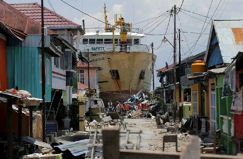 A ship swept ashore by Friday’s tsunami sits in the middle of a neighborhood Tuesday in Donggala in Central Sulawesi, Indonesia. People in the Donggala region say they are not getting help after the disaster. 