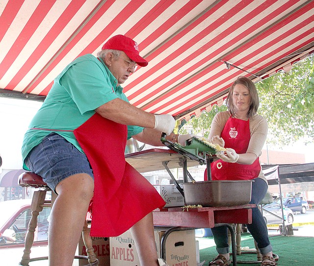 FILE PHOTO Doug Hulse and Megan Hudgens slice and hand out fresh apple samples to visitors at the 2017 Arkansas Apple Festival in Lincoln. The tent is always the most popular one every year and is a tribute to the apple industry that once dominated western Washington County. The 43rd annual Festival will be this weekend, Friday-Sunday.