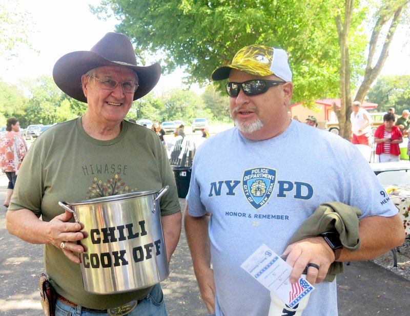 Westside Eagle Observer/SUSAN HOLLAND Larry Weihe, chairman of the chili cookoff at the Hiwasse fall festival, displays the chili pot trophy won by Chuck Skaggs, Gravette chief of police, at the annual festival. Skaggs beat out seven other chili cooks in the competition, received a $50 cash prize, a festival T-shirt and a coffee mug and then signed his name to the traveling trophy.