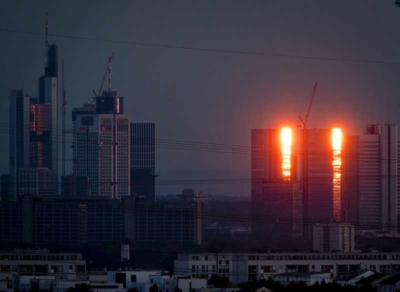 The towers of the Deutsche Bank are illuminated by the setting sun in Frankfurt, Germany, Sunday, Sept. 30, 2018. (AP Photo/Michael Probst)