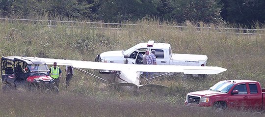 The Sentinel-Record/Richard Rasmussen SAFELY DOWN: Emergency personnel examine a small plane that reportedly made an emergency landing in the infield of a thoroughbred training track at Double M Stables off Crystal Hill Road in western Garland County Wednesday afternoon.