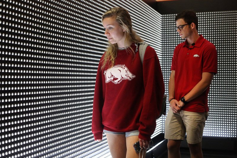 NWA Democrat-Gazette/DAVID GOTTSCHALK NWA Democrat-Gazette/DAVID GOTTSCHALK Lauren Hacala (left), a sophomore at the University of Arkansas, and Shay Longmate, a junior, walk Wednesday through the Prescribed to Death: A Memorial to the Victims of the Opioid Crisis that features a wall constructed of 22,000 carved pills, each representing the face of someone who fatally overdosed on a prescribed opioid in 2015. The memorial is inside the Arkansas Union on the campus in Fayetteville and offers resources to help visitors both safely dispose of unused pills in their homes and facilitate discussions with prescribers about alternatives. The Associated Student Government is a supporting partner in the exhibit that is part of the ASG's ongoing effort to educate the campus about the danger of opioids. The Exhibit is open to the public through Tuesday, October 9.