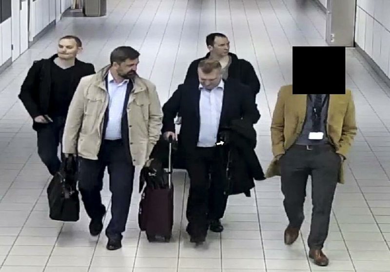 Four Russian military intelligence agency officers head for a flight out of the Netherlands on Oct. 4 after they were expelled for trying to hack into the computers of the Organization for the Prohibition of Chemical Weapons. The case is among several cited Thursday in indictments by U.S., British, Australian and Dutch officials. 