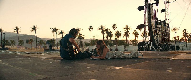 Jackson Maine (Bradley Cooper) picks out a melody for Ally (Lady Gaga) as the two write a song together in A Star Is Born. 