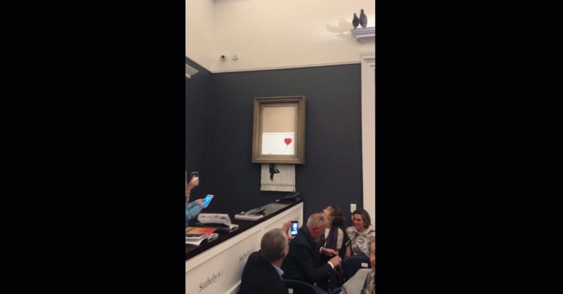 In this grab taken from video on Friday, Oct. 5, 2018 people watch as the spray-painted canvas &quot;Girl with Balloon&quot; by artist Banksy is shredded at Sotheby's, in London, A Banksy artwork self-destructed moments after being sold at auction for 1.04 million pounds ($1.4 million), in a prank apparently orchestrated by the elusive street artist. (Pierre Koukjian via AP)