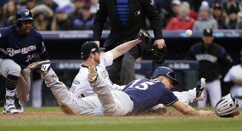 The Milwaukee Brewers’ Erik Kratz slides safely into home plate to score on a wild pitch by Colorado Rockies relief pitcher Scott Oberg, who tries to field the throw from catcher Tony Wolters in the sixth inning of Game 3 of the National League division series Sunday in Denver. Kratz had three hits as the Brewers won 6-0 to sweep the Rockies and move on to the NL Championship Series.