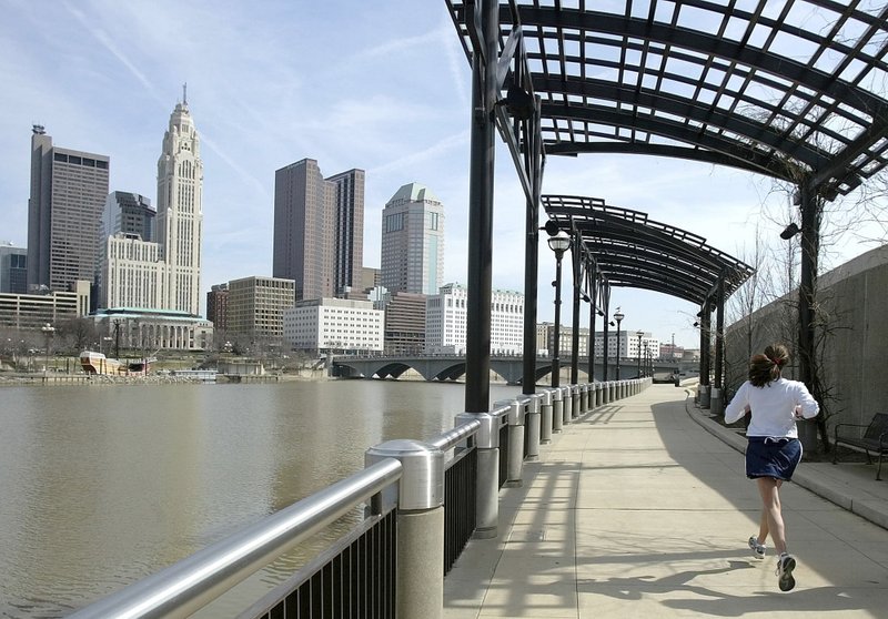 FILE - In this March 15, 2004, file photo, a woman runs the Franklinton floodwall next to the Scioto River in Columbus, Ohio. The largest city named for Christopher Columbus has called off its observance of the holiday named for the explorer. Offices in Columbus, Ohio, will remain open Monday, Oct. 8, 2018, and close on Veterans Day instead. (AP Photo/Jay LaPrete, File)