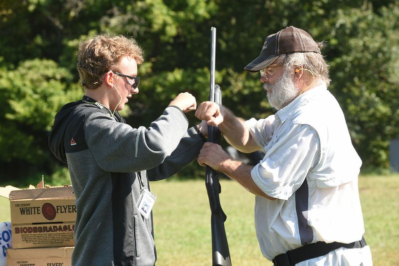 NWA Democrat-Gazette/FLIP PUTTHOFF Lonnie Robinson (right) congratulates Trenton Laughlin after Laughlin broke five out of six targets his first time to shoot a shotgun.