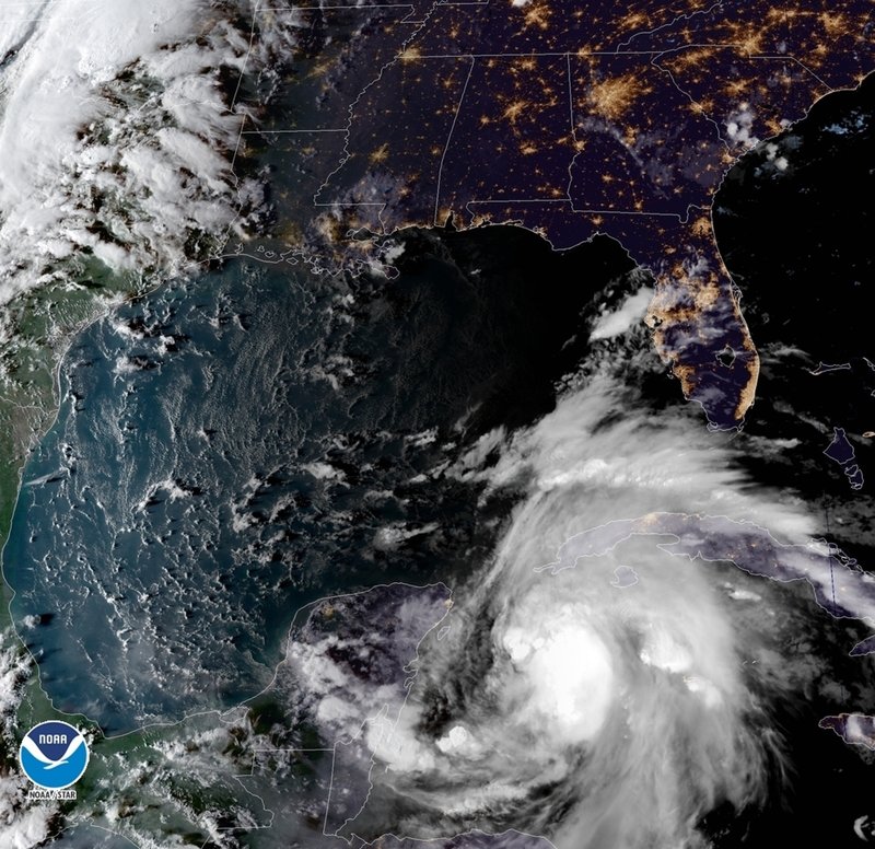 The Associated Press TROPICAL WEATHER: This satellite image provided by the National Oceanic and Atmospheric Administration shows a view of Tropical Storm Michael, lower right, churning as it heads toward the Florida Panhandle, Sunday, at 6:52 p.m. Eastern Time.