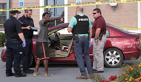 Emergency medical personnel and Hot Springs police speak to a man identified as Demarion Banks, of Hot Springs, who drove to the Hot Springs Police Department in a bullet-riddled car minutes after a shooting erupted at Tire Express, 635 E. Grand Ave., on Oct. 8, 2018. - Photo by Mark Gregory of The Sentinel-Record