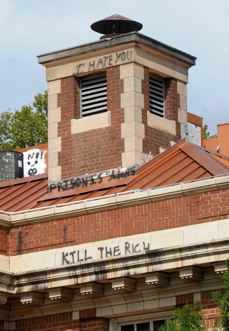 NWA Democrat-Gazette/DAVID GOTTSCHALK Graffiti is visible Monday on the south-facing side of The Old Post Office building in the center of the square in Fayetteville. Words and markings, including profanity, are visible on other areas of the building.