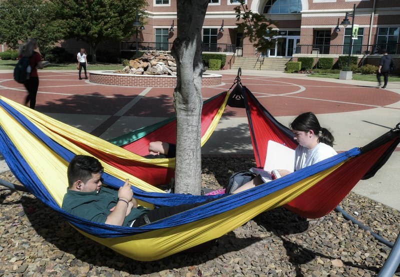 NWA Democrat-Gazette/CHARLIE KAIJO Luis Duran of Springdale and Elisabeth Sugg of Springdale (from left) relax on hammocks between their classes Monday at the Northwest Arkansas Community College in Rogers.