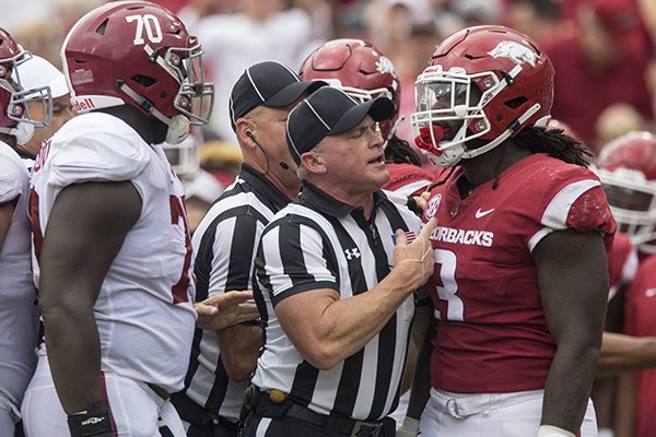 An official separates Arkansas defensive end McTelvin Agim and Alabama offensive lineman Alex Leatherwood after a play in the second quarter of a game Saturday, Oct. 6, 2018, at Razorback Stadium in Fayetteville. 