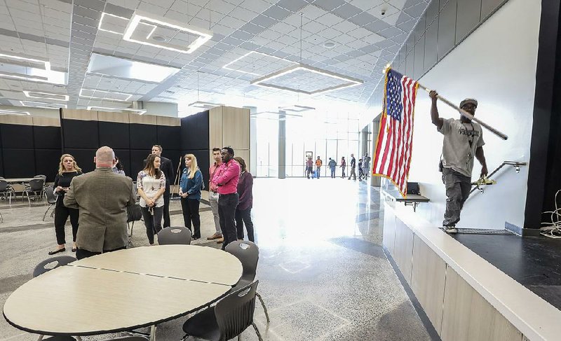Custodian Corey Taylor returns an American flag to the cafetorium as Principal Lance LeVar (back to camera) leads a tour of the new Robinson Middle School in west Little Rock in this Tuesday, Oct. 9, 2018, file photo. A ribbon-cutting ceremony was held that Tuesday morning to celebrate the completion of the school, part of the Pulaski County Special School District. 