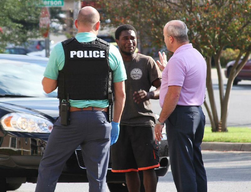 Hot Springs Police Department detectives talk with shooting suspect Demarion Banks (center) in the Police Department parking lot after Monday’s gunfire. 