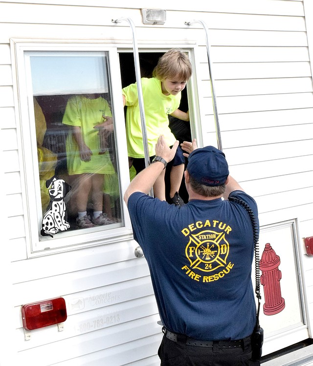 Westside Eagle Observer/MIKE ECKELS With the help of a Decatur firefighter, Jackson Clayton climbs out of a window of the Decatur Fire Department smoke simulation trailer to safety. Clayton was one of many students of Decatur Pre-K and Northside Elementary who participated in the Fire Safety Day held in the parking lot of the school on Oct. 5.