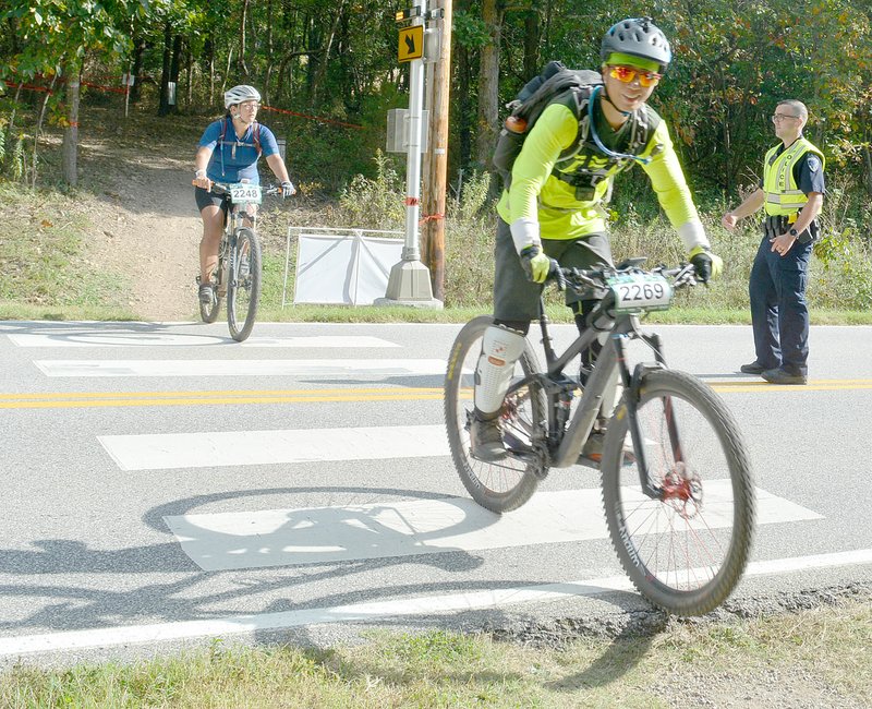 Keith Bryant/The Weekly Vista Bella Vista police officer Joshua Hendry, right, background, directs Oz Trails Off Road riders across Euston Road.