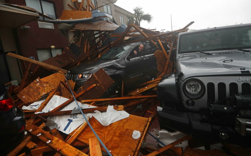 A woman checks on her vehicle as Hurricane Michael passes through, after the hotel canopy had just collapsed, in Panama City Beach, Fla., on Wednesday, Oct. 10, 2018. 