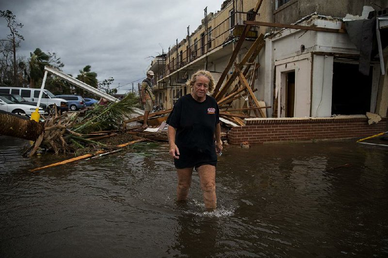 A woman walks through floodwater and storm debris near a damaged apartment building Wednesday in Panama City, Fla., after Hurricane Michael slammed the Gulf Coast. 
