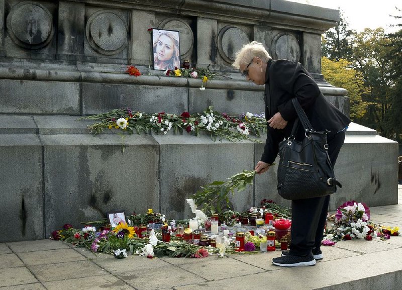 A woman leaves flowers Wednesday near the photo of Viktoria Marinova on the Liberty Monument in Ruse, Bulgaria. The television journalist was raped and strangled Saturday.