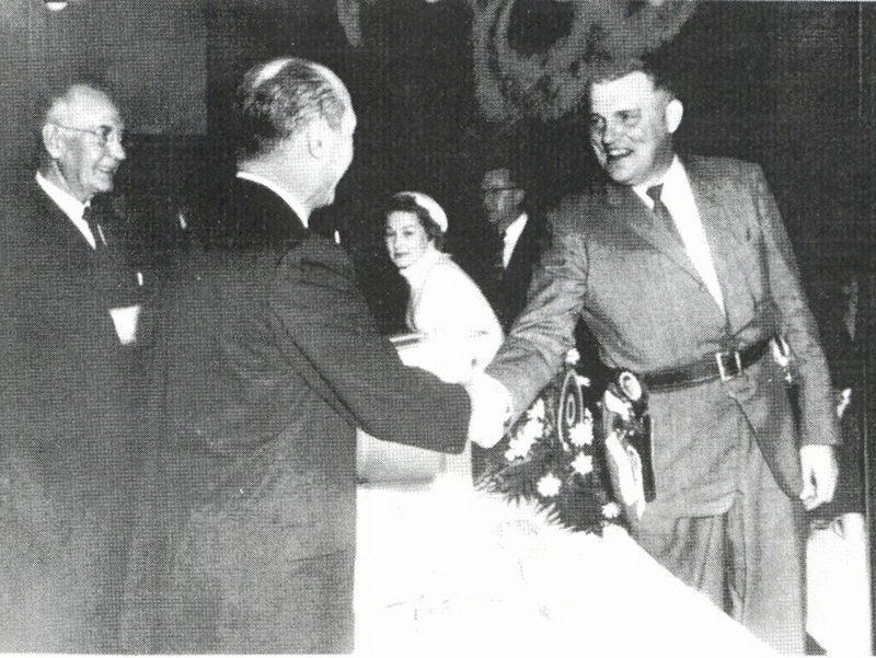 COURTESY PHOTO Cass Hough shakes hands with Gene Harris on Dec. 10, 1957, at the Rogers Chamber of Commerce banquet following the city's ground-breaking ceremony for Daisy Maunfacturing. Earl Harris of Harris Bakery and Gene Harris of the American National Bank (no relation to Earl Harris) were instrumental in bringing Daisy to Rogers.