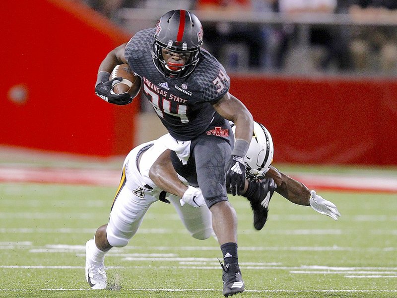 SUN FELLED: Arkansas State running back Marcel Murray (34) attempts to escape a tackle by Appalachian State defensive back Josh Thomas in the first quarter of the Red Wolves' 35-9 loss on Tuesday at Centennial Bank Stadium in Jonesboro.