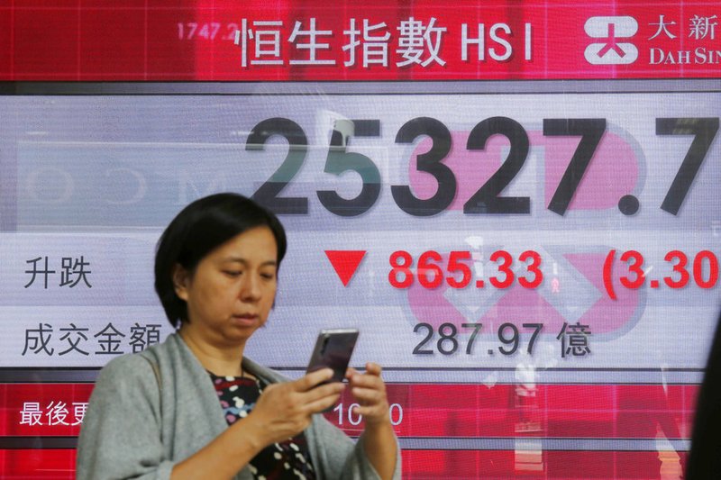 A man walks past an electronic board showing Hong Kong share index outside a bank In Hong Kong on Thursday, Oct. 11, 2018. 