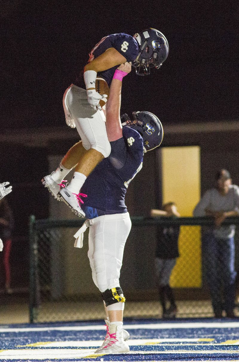 Prairie vs Shiloh Christian - Logan Kallesen (73) lifts teammate Jaret Russ (11) up in the air after scoring a touchdown against Prairie Grove at Champions Stadium, Springdale, AR on Friday, October5, 2018. Russ and the Saints are off to a 5-1 start this season. Special to NWA Democrat-Gazette/ David Beach