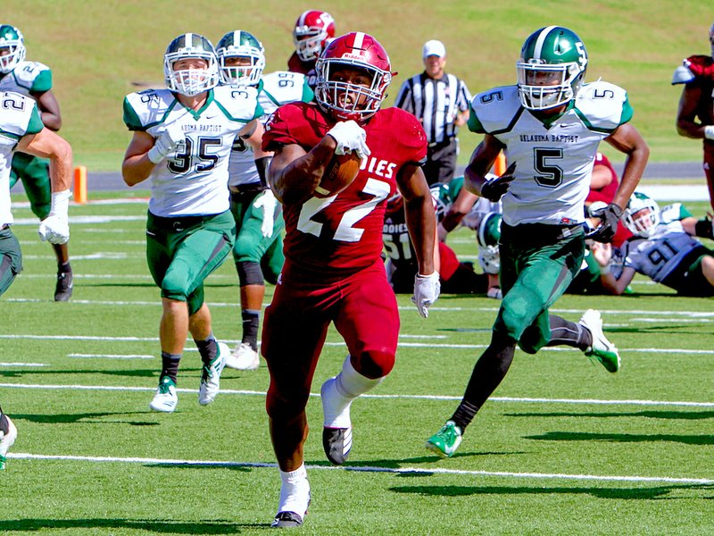 Submitted photo BREAKING: Henderson State running back Logan Moragne breaks away from Oklahoma Baptist defenders Saturday during the Reddies' 56-21 victory in Arkadelphia. Photo by Steve Fellers, courtesy of Henderson State Athletic Communications.