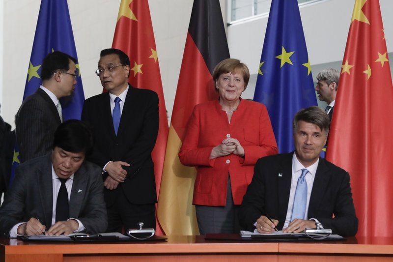 FILE - In this July 9, 2018 file photo German Chancellor Angela Merkel, second from right, and Chinese Premier Li Keqiang, third from left, attend a contracts signing ceremony between German car maker BMW CEO Harald Krueger, right, and Qi Yumin CEO of the Brilliance Group, left front, during a meeting in the chancellery in Berlin. German automaker BMW said Thursday, Oct. 11, 2018 it is taking a majority stake in its China joint venture and investing 3 billion euros in future production there as it prepares to meet increased demand for electric vehicles. (AP Photo/Markus Schreiber, file)