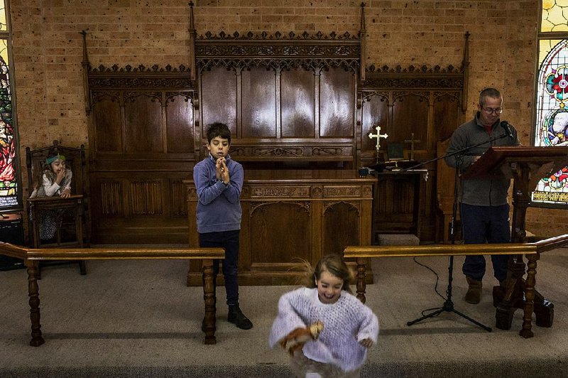 The Rev. Bernard Gabbott prepares for a Sunday service as his children play at the Anglican church in Wee Waa, New South Wales, Australia. The specter of harder times hangs over a rural Australian town where the worst of the drought has yet to come. 