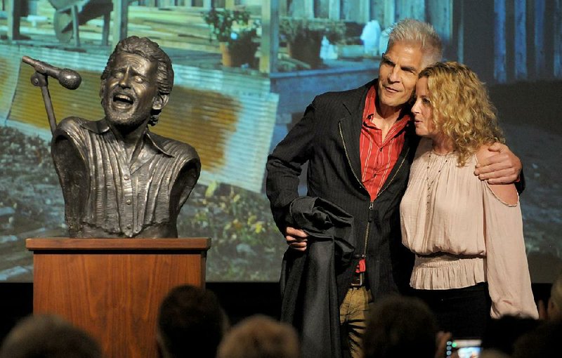 Amy Helm, daughter of musician Levon Helm, and artist Kevin Kresse unveil a bronze bust of her late father Friday in downtown Fayetteville.