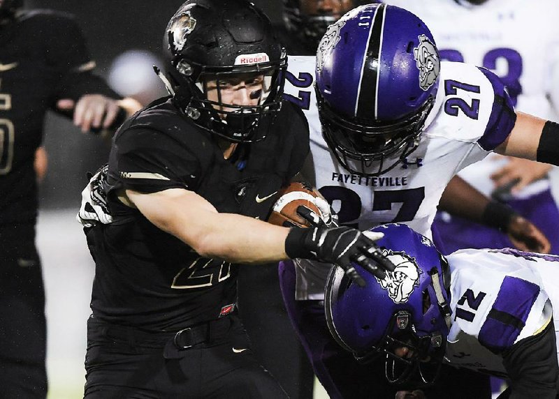 Bentonville’s Harrison Campbell (left) tries to break away from Fayetteville’s Carsten Johnson (27) and Marquez Douglas during Friday night’s game at Bentonville.