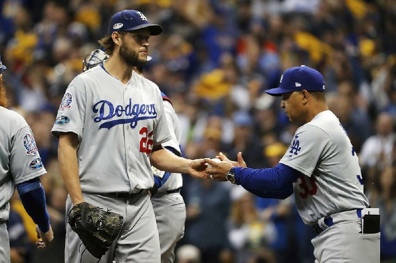 Los Angeles Dodgers pitcher Clayton Kershaw (left) hands the ball to Manager Dave Roberts as he leaves the mound Friday night in the Dodgers’ 6-5 loss to the Milwaukee Brewers in Game 1 of the National League Championship Series. 