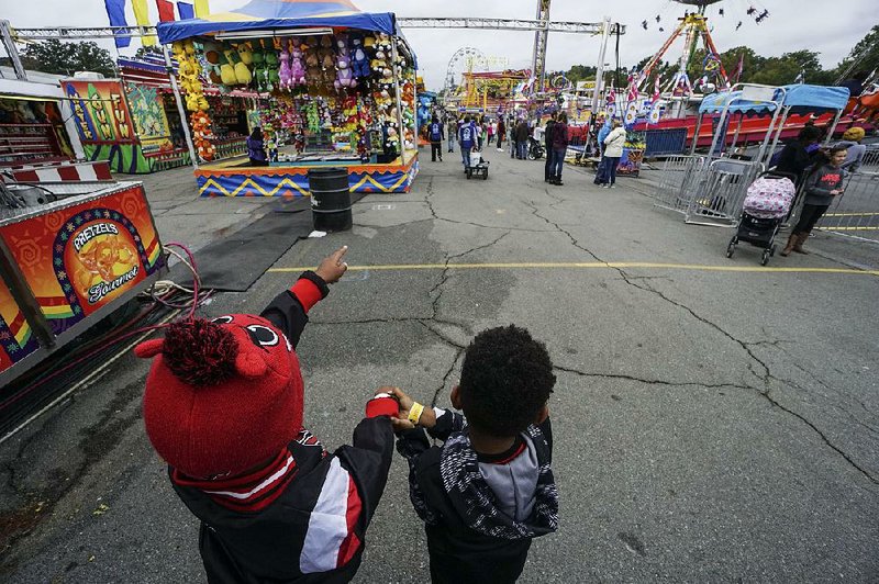 Friends Seth (left) and Gabe plan their ride strategy Saturday on the midway section of the Arkansas State Fair. 