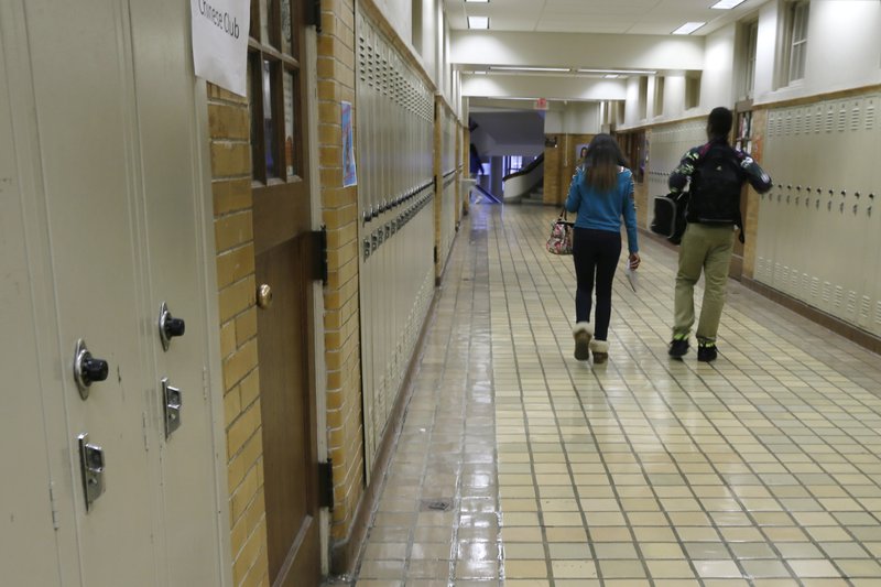FILE - In this Monday, Jan. 13, 2014, file photo, two students walk in a hallway at Little Rock Central High School in Little Rock, Ark. Dozens of Arkansas schools have continued to suspend children who repeatedly miss classes five years after the state banned the use of out-of-school suspension as a punishment for truancy. Because there's no language in the law that specifies which state agency is responsible for its enforcement, it has essentially gone unenforced since its passage in 2013. (AP Photo/Danny Johnston, File)
