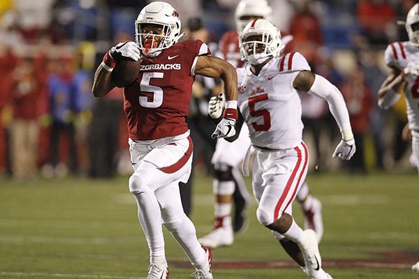 Arkansas running back Rakeem Boyd (left) races to the end zone for a 69-yard touchdown during the first quarter on Saturday, Oct. 13, 2018, at War Memorial Stadium in Little Rock.
