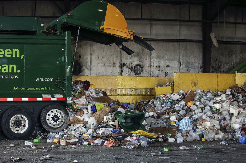 Recyclables are unloaded from a truck Wednesday at the Waste Management recycling facility in Little Rock. Little Rock, North Little Rock and Sherwood are phasing out curbside glass recycling. 