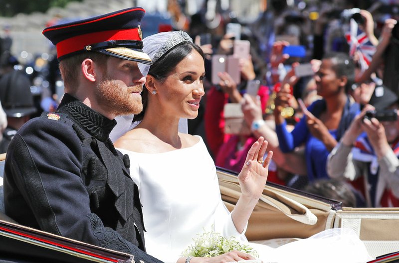 In this file photo dated Saturday, May 19, 2018, Britain's Prince Harry and his bride Meghan Markle, ride in a carriage after their wedding ceremony at St. George's Chapel in Windsor Castle in Windsor, near London, England. Kensington Palace announced Monday Oct. 15, 2018, that Prince Harry and his wife the Duchess of Sussex are expecting a child in spring 2019. (AP Photo/Frank Augstein, FILE)