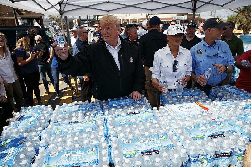 President Donald Trump and first lady Melania Trump hand out water Monday in Lynn Haven, Fla., during a visit to areas devastated by Hurricane Michael.