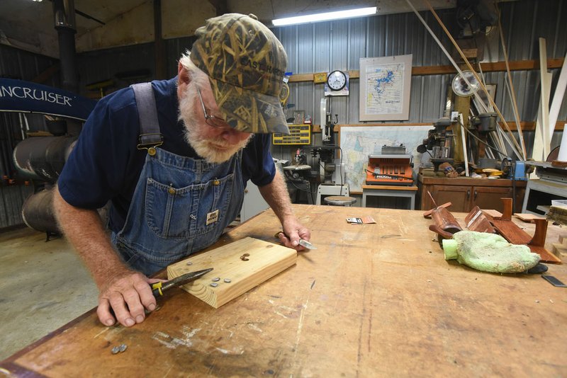 NWA Democrat-Gazette/FLIP PUTTHOFF James Cox checks the inside of persimmon seeds last week for knife, fork or spoon patterns. Folklore says the seeds can predict the coming winter weather.