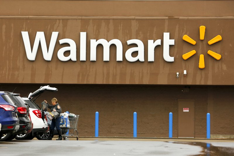 In this Feb. 22, 2018, file photo, a shopper loads her car after shopping at a Walmart in Pittsburgh. Walmart trimmed its annual profit outlook citing the $16 billion acquisition of the Indian online retailer Flipkart, its biggest deal ever. The company said on Tuesday, Oct. 16, however, that online sales growth would slow to 35 percent, from last quarter's 40 percent growth. (AP Photo/Gene J. Puskar, File)