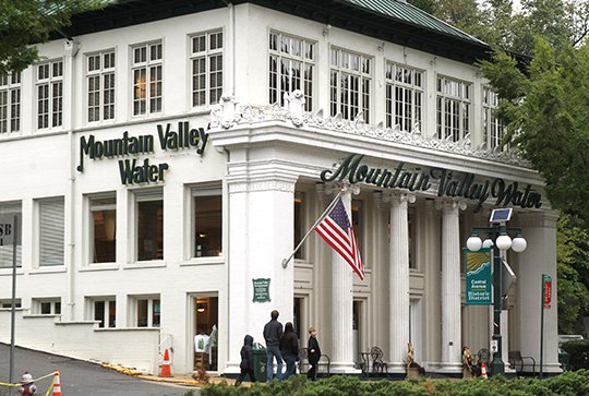 The Sentinel-Record/Richard Rasmussen BUSINESS AS USUAL: Pedestrians stroll past the Mountain Valley Spring Co. Visitor Center and Museum at 150 Central Ave. Tuesday. Cott Corp. announced its acquisition of the bottled water company Monday for $78.5 million.