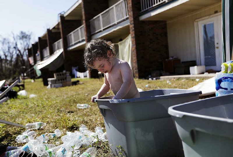 Gaige Williams, 2, cools off in a plastic container outside of the storm-damaged motel in Panama City, Fla., where he and his family live after being uprooted by Hurricane Michael. 