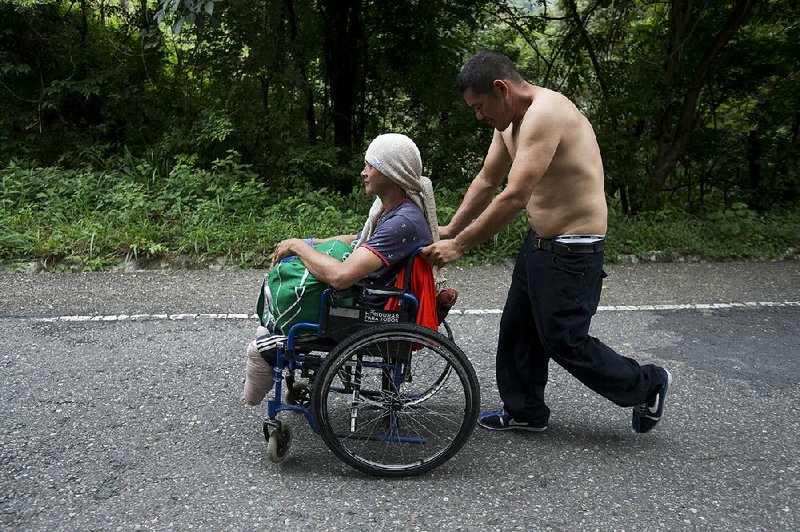 Honduran migrant Omar Orella pushes fellow migrant Nery Maldonado Tejeda, who lost his legs while trying to ride a freight train in his first attempt to reach the United States. 