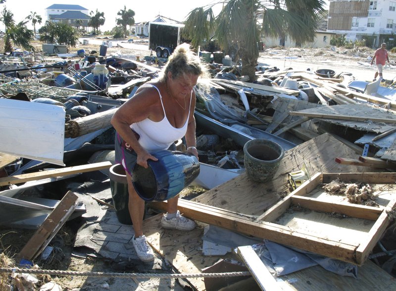 In this Oct. 14, 2018 photo Dena Frost salvages an unbroken clay pot from the wreckage of her pottery business in Mexico Beach, Fla. For decades, the town has persisted as a stubbornly middlebrow enclave on what residents proudly refer to as Florida's &quot;Forgotten Coast.&quot; Businesses are locally owned. While some locals owned posh homes that overlooked the beach on stilts, many lived in mobile homes. (AP Photo/Russ Bynum)