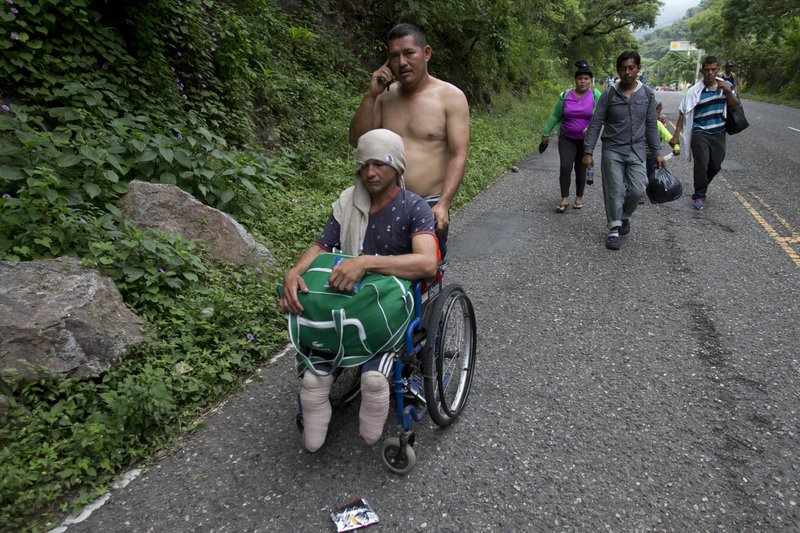 Honduran migrant Omar Orella pushes fellow migrant Nery Maldonado Tejeda in a wheelchair, as they travel with hundreds of other Honduran migrants making their way the U.S., near Chiquimula, Guatemala, Tuesday, Oct. 16, 2018. Maldonado said he lost his legs in 2015 while riding &quot;The Beast,&quot; a northern-bound cargo train in Mexico, and that this is his second attempt to reach the U.S. (AP Photo/Moises Castillo)