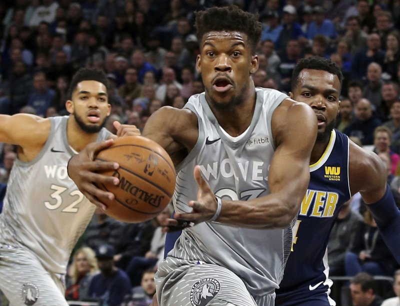 FILE - In this April 11, 2018, file photo, Minnesota Timberwolves' Jimmy Butler, center, drives to the basket ahead of Denver Nuggets' Paul Millsap, right, during the first half of an NBA basketball game in Minneapolis. Butler joined the Timberwolves for practice again on Sunday, Oct. 14, 2018, with the season opener just three days away despite his request to be traded. (AP Photo/Jim Mone, File)