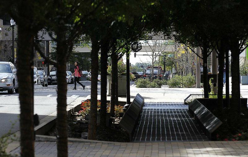 A pedestrian crosses the recently completed Main Street creative corridor Wednesday in downtown Little Rock. The most recent work in the 600 and 700 blocks of the project includes porous pavers, rain gardens and a vegetative wall. 
