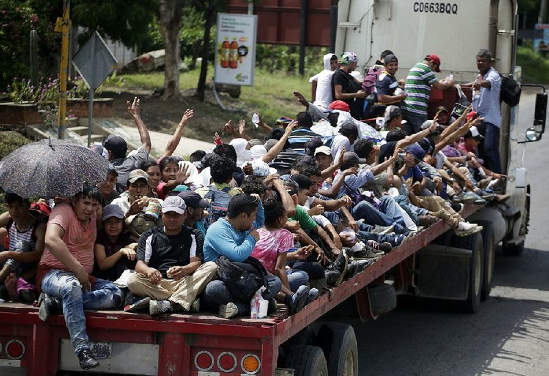 Honduran migrants, who are traveling to the United States as a group, get a free ride Wednesday on the back of a trailer truck flatbed as they make their way through Teculutan, Guatemala. 